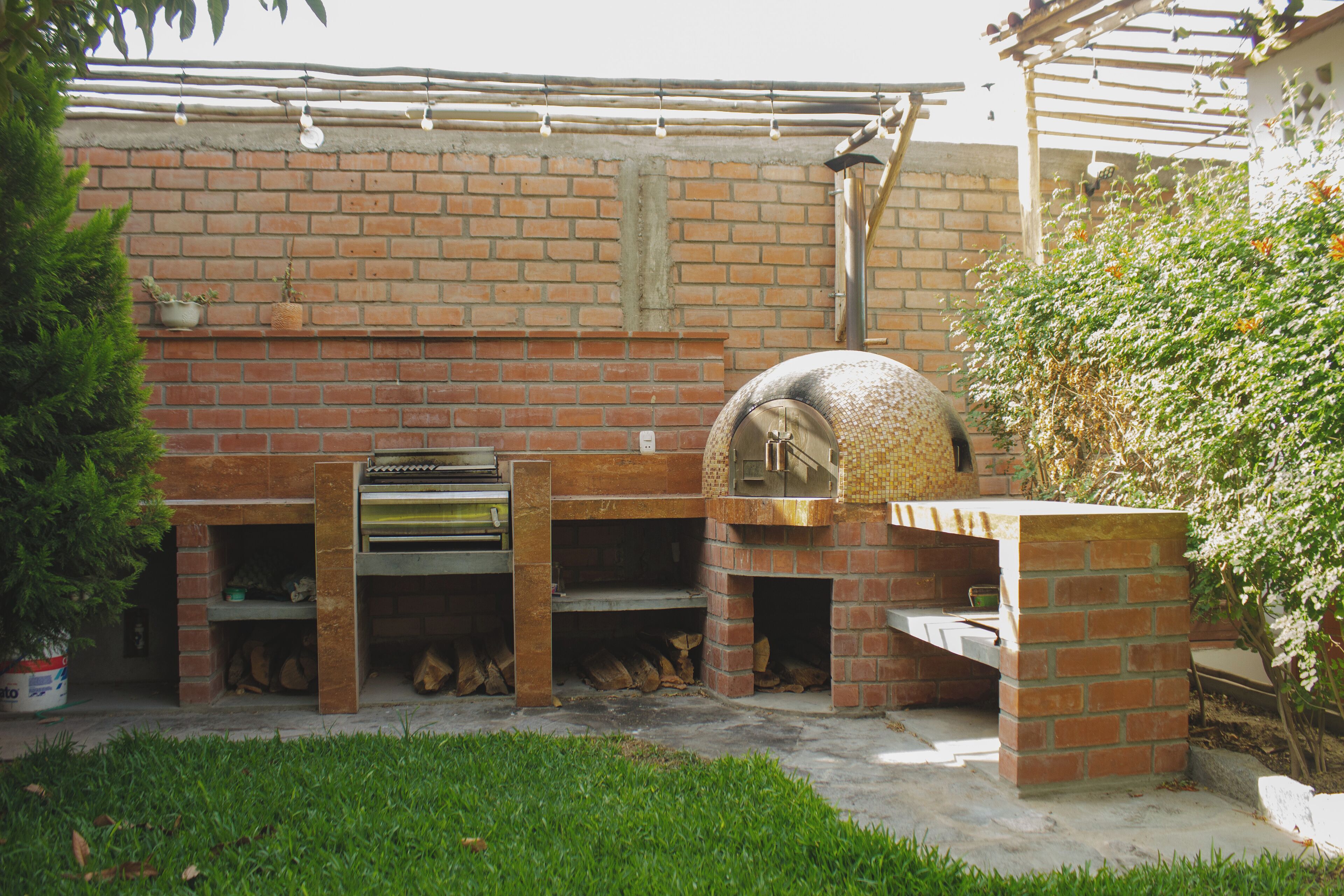A brick outdoor kitchen with a pizza oven and a grill.