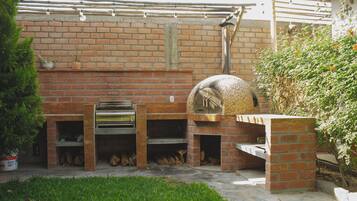 A brick outdoor kitchen with a pizza oven and a grill.