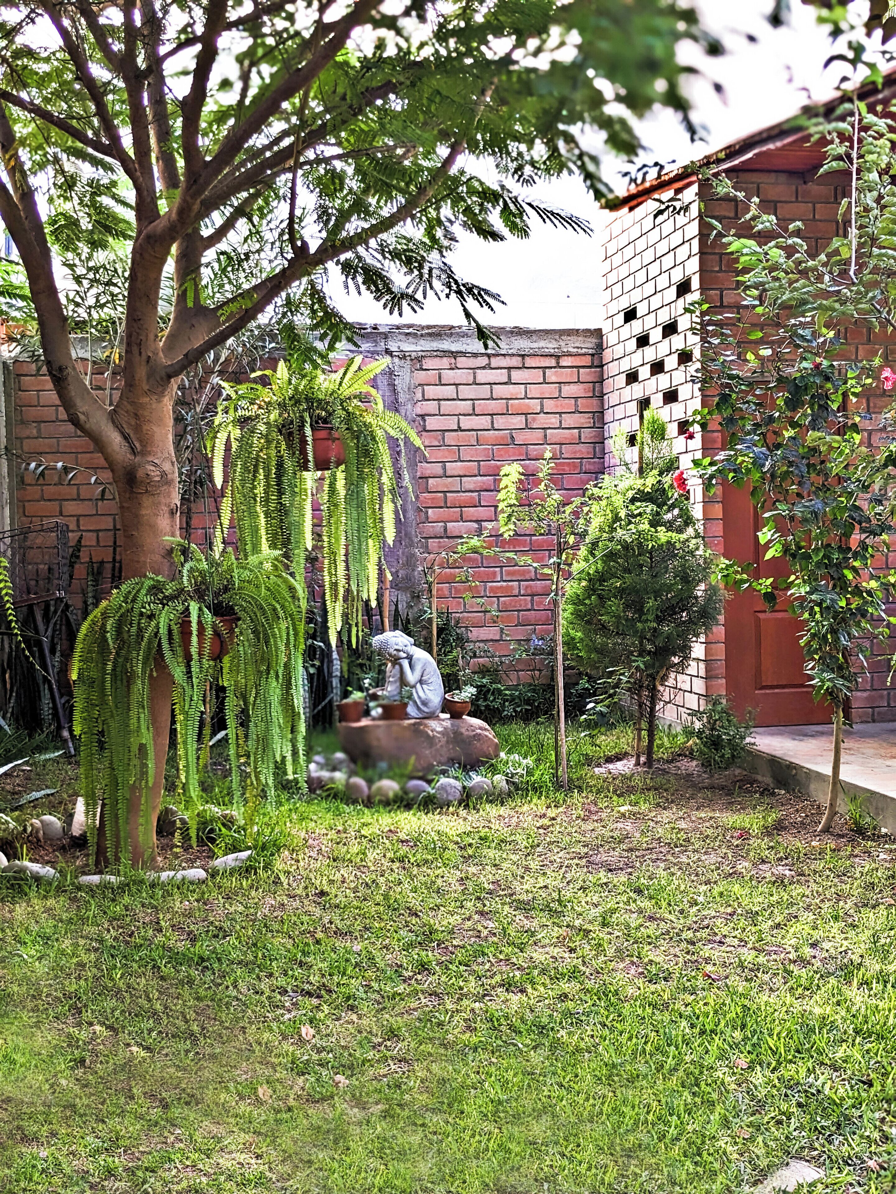 Un jardin agrémenté de diverses plantes, d’une statue et d’un mur en briques.