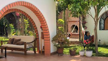 A courtyard with a brick archway, a white sofa, and potted plants.