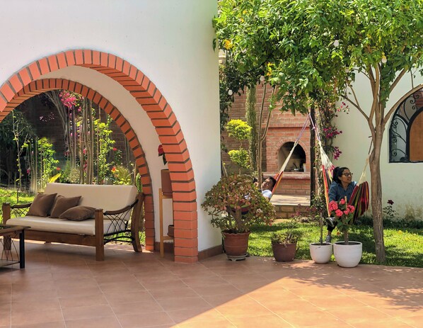 A courtyard with a brick archway, a white sofa, and potted plants.