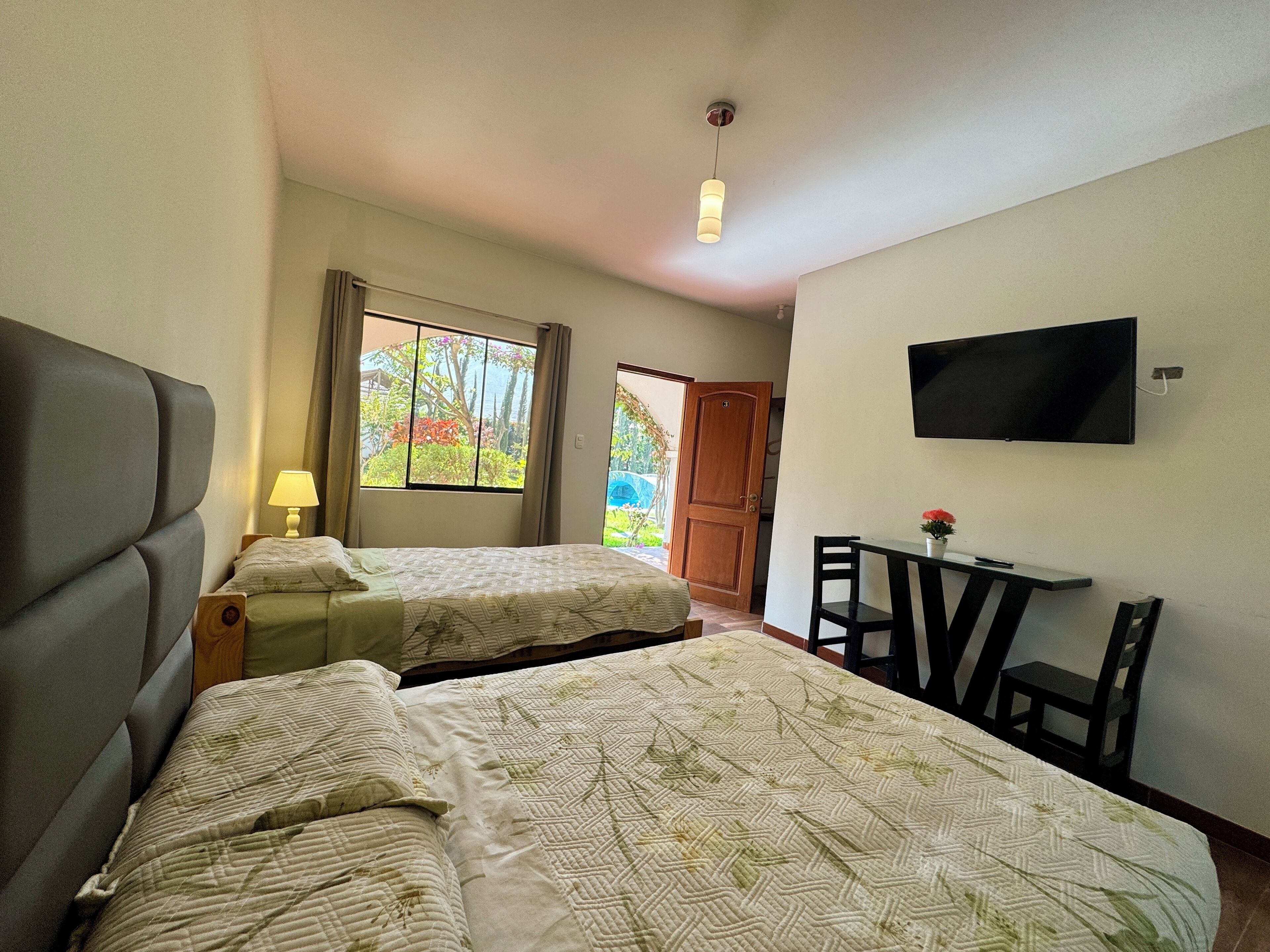 Ein Hotelzimmer mit zwei Betten, einem Schreibtisch, einem Sessel, einem Fernseher und einem Fenster mit Vorhängen.