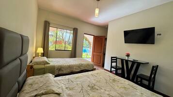 Ein Hotelzimmer mit zwei Betten, einem Schreibtisch, einem Sessel, einem Fernseher und einem Fenster mit Vorhängen.