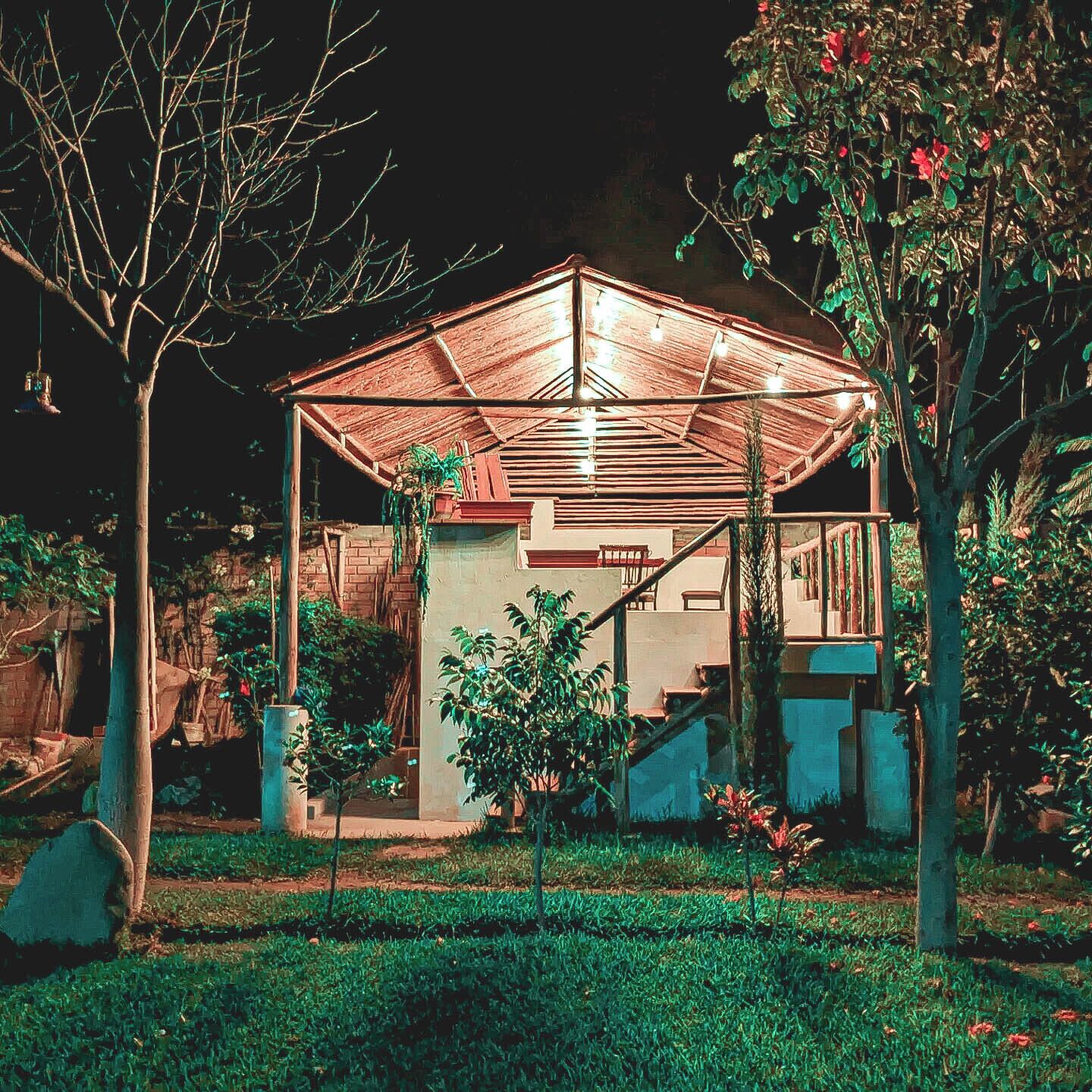 A covered outdoor area with a wooden structure, steps leading up to a building, and potted plants.