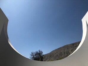Una estructura arquitectónica circular con cielo despejado y una montaña al fondo.