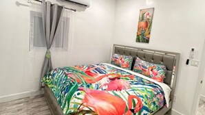 A bedroom with a bed, a ceiling fan, an air conditioning unit, a painting, and a fluffy rug. - 5 mins walk or rent a bike to ride to Turtle Beach. (Exuma)