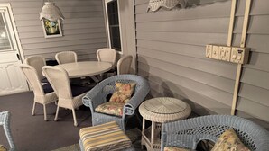 A cozy outdoor seating area with wicker furniture, a round table, and a small side table.
