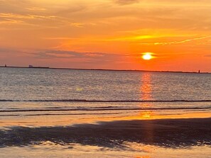 A sunset over a calm sea with a distant shoreline. - Cozy beach cottage, steps from Lewes Beach (Lewes)