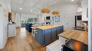 Een moderne keuken met houten werkbladen, een centraal kookeiland en hangende lampen.