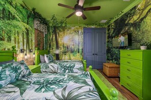 Une pièce comprenant un lit, une commode, un ventilateur de plafond et une porte.