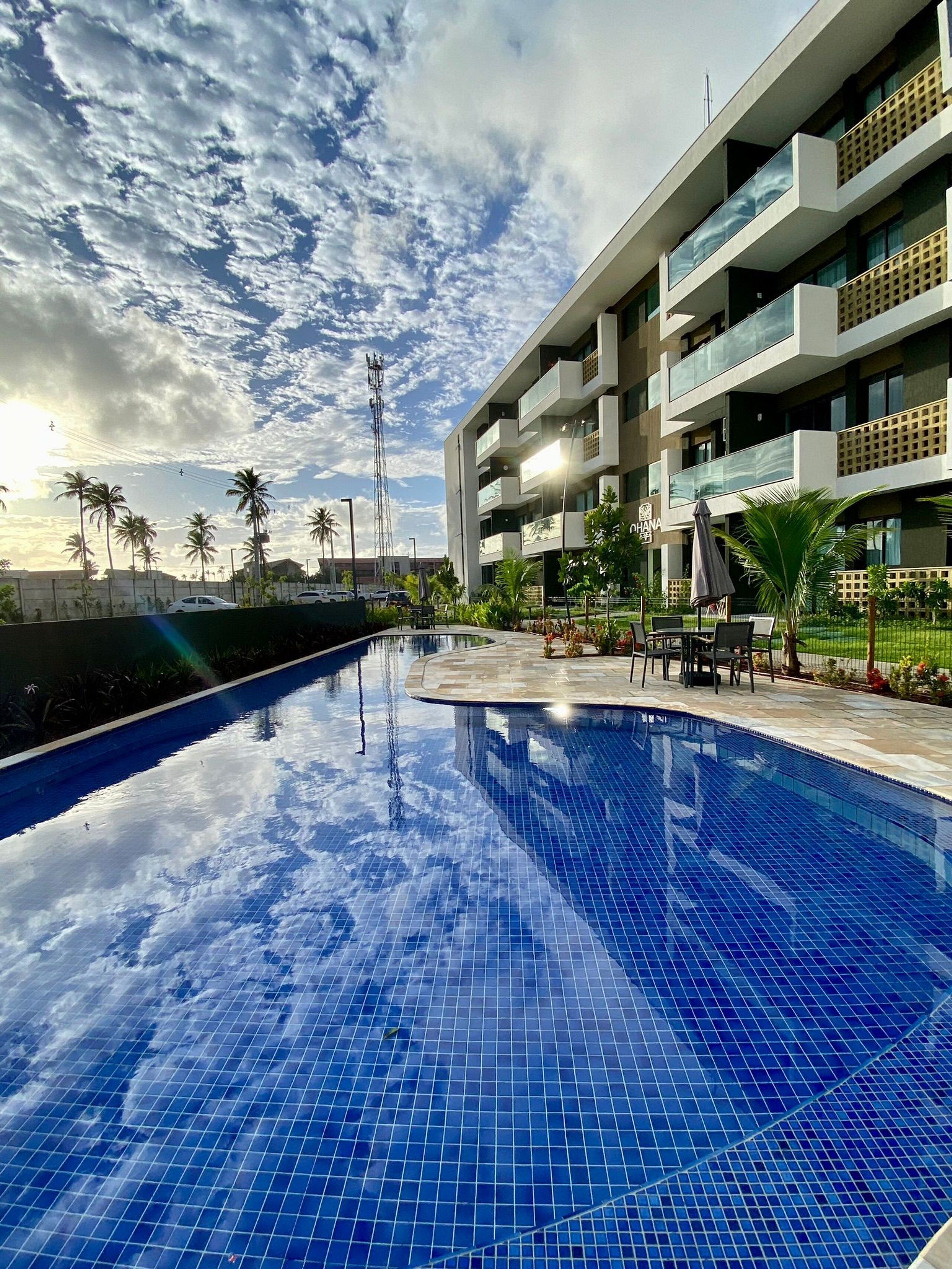 Un hotel moderno con piscina, zona de estar exterior y vista despejada al cielo.