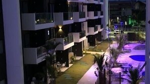 Een modern hotel met meerdere verdiepingen, balkons, een aangelegde binnentuin en een zwembad.