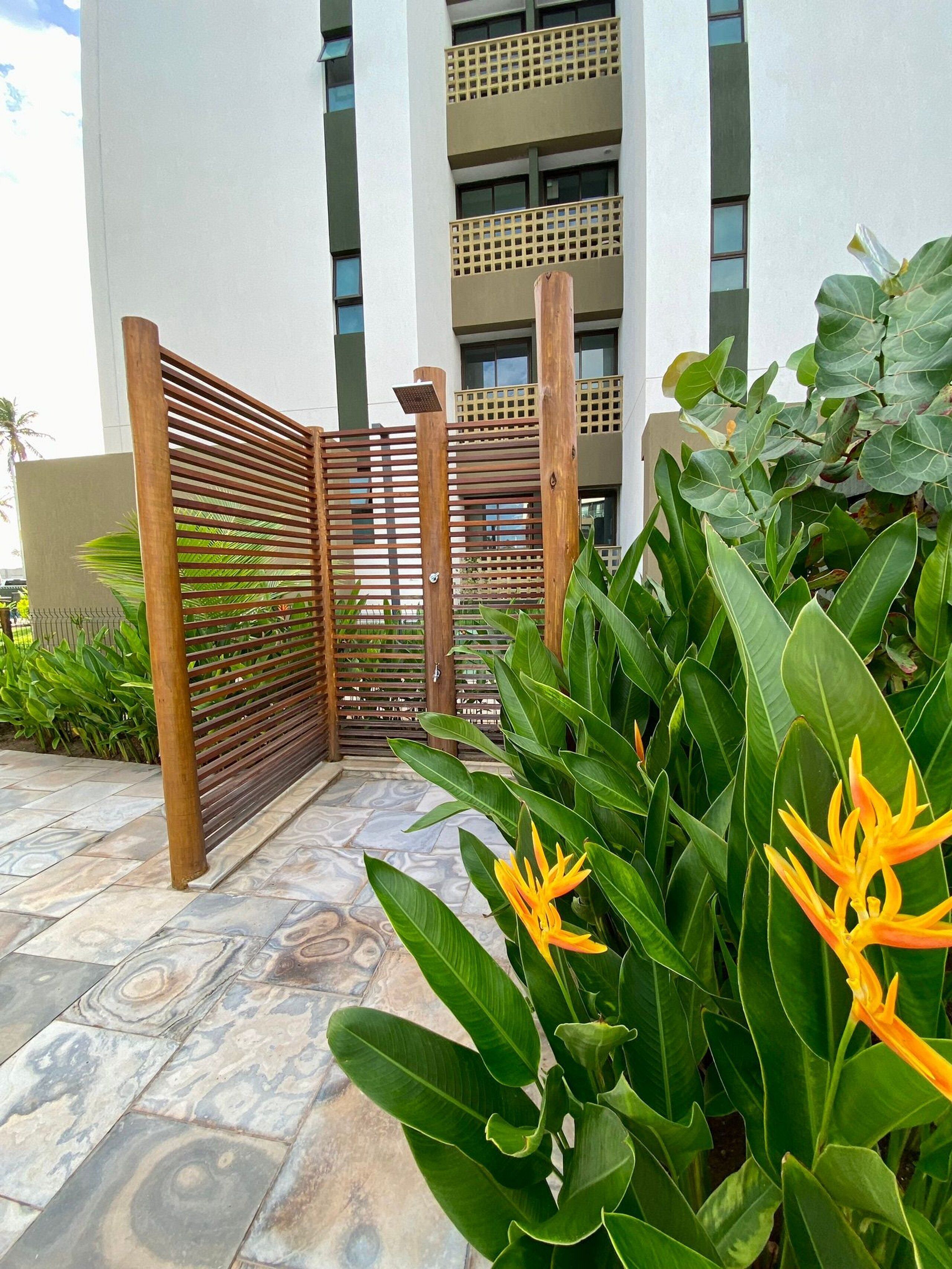 A gated entrance with a wooden fence and lush green plants.