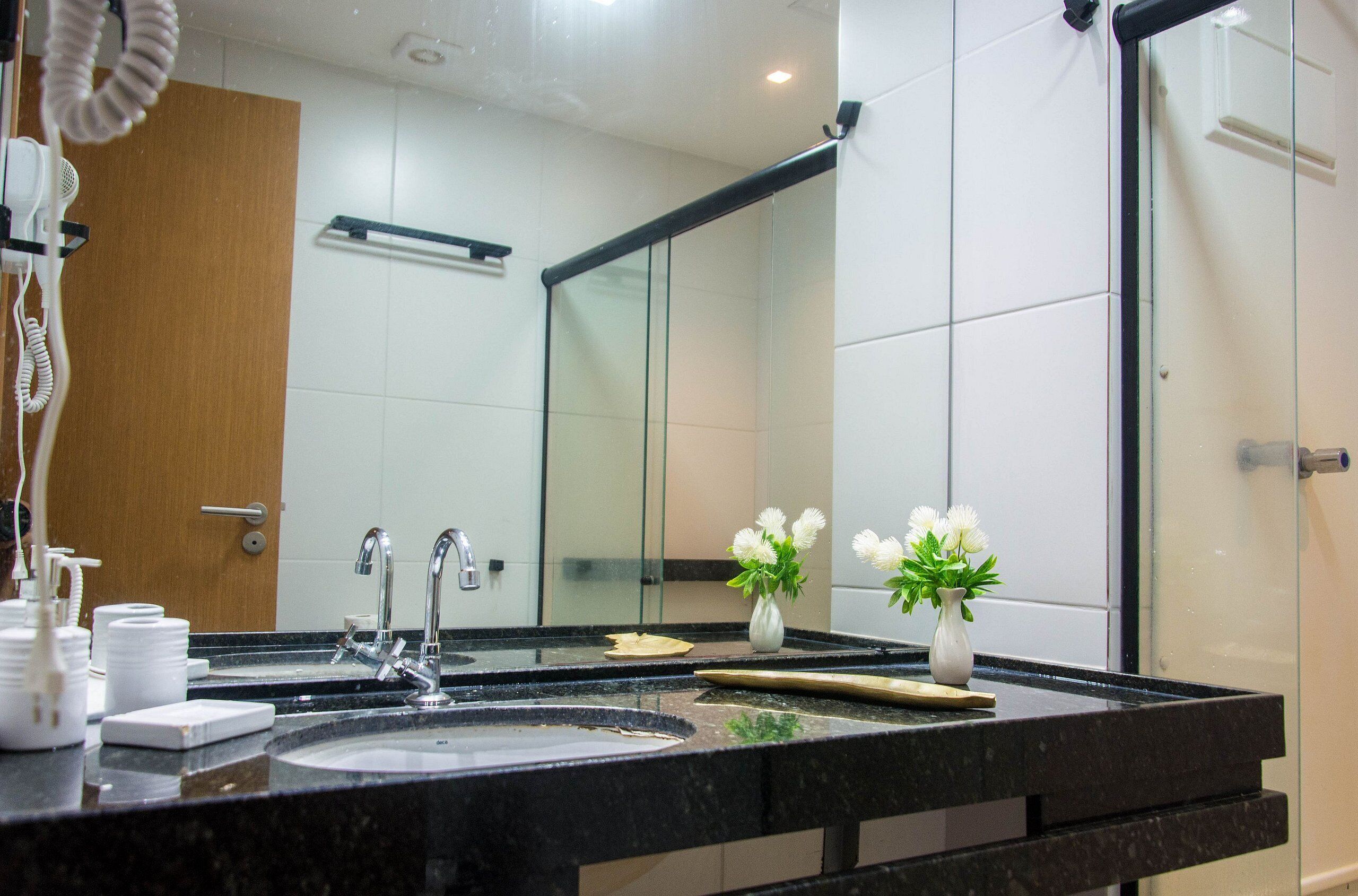 Une salle de bain moderne avec un grand miroir, un lavabo et un espace douche.
