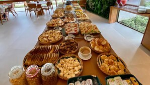 Een buffet met diverse gerechten en sauzen, in een ruimte met grote ramen en een groene wand.