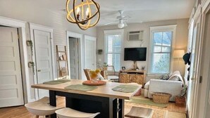 A modern kitchen with a central island, bar stools, a ceiling fan, and a television in the background. - Seaglass Village Gem! 3 night min, close to Ogunquit Beach (Wells)