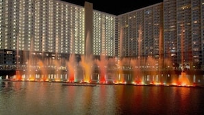 Une vue nocturne d’un hôtel, avec plusieurs immeubles de grande hauteur et un spectacle de jeux d’eau.