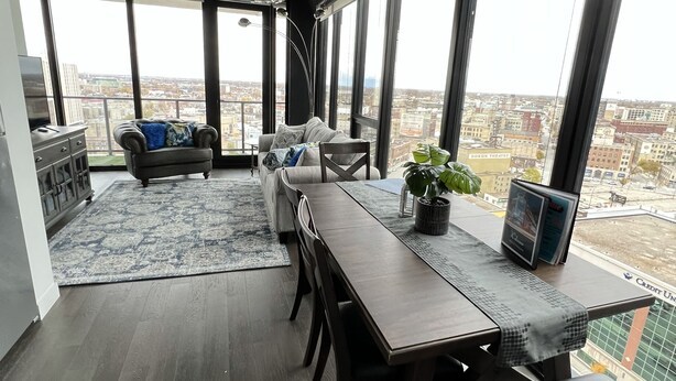 Un balcon spacieux avec un coin repas, de grandes fenêtres et une vue sur le paysage urbain.