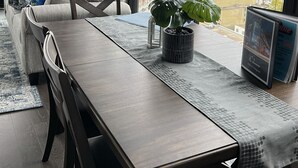 Un salon moderne avec un canapé, une table à manger et une plante en pot. De grandes fenêtres offrent une vue sur la ville.