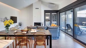 A modern living room with a dining area, large windows, and a view of a pool. - Villa with swimming pool and playground (Valbandon)
