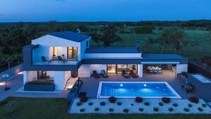 A modern two-story house with a swimming pool, outdoor seating, and a well-maintained garden. - Villa with swimming pool and playground (Valbandon)