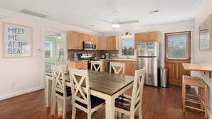 Una cocina moderna con armarios de madera, electrodomésticos de acero inoxidable y un comedor con mesa y sillas de madera.