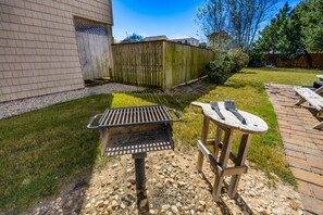An outdoor patio area with a grill, a wooden table, and a deck.