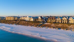 Un hôtel situé sur la côte, composé de plusieurs bâtiments, avec une plage de sable et un ciel bleu dégagé.