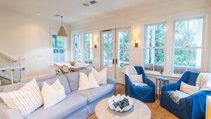 Un salon spacieux avec un canapé gris, des fauteuils bleus et une table basse ronde.
