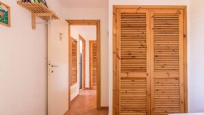 Un pasillo con puertas de madera, una cama y una estantería con objetos.