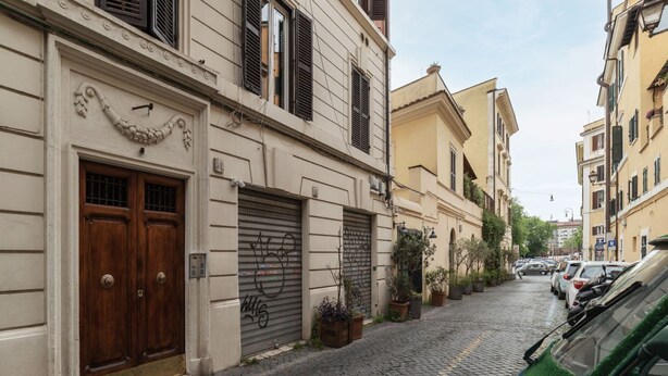 Un carrer empedrat i estret flanquejat per edificis històrics, amb una porta doble de fusta i una porta de garatge amb obertura automàtica.