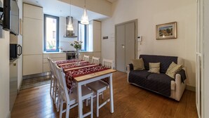 Un espai modern d'estar amb zona de menjador, sofà i cuina.