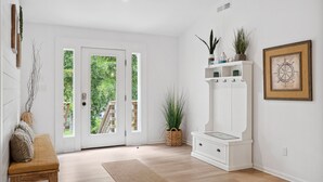 A clean, modern entryway with a bench, a white console table with plants, and a framed picture on the wall. - Casa Del Mar - Chic, Large Fenced Yard, Pet Friendly, 0.3 mi to Beach (Folly Beach)