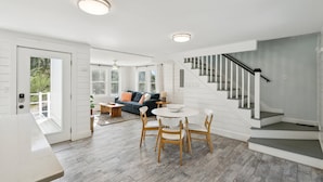 Ein geräumiger Wohnbereich mit Treppe, einem Esstisch mit Stühlen und einer Couch.