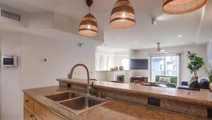 A kitchen with granite countertops, stainless steel sink, and pendant lighting.