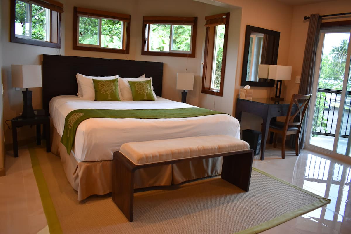 Une chambre à coucher avec un grand lit, une banquette, deux tables de chevet, un bureau et une chaise.