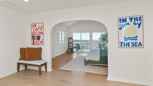 Ein geräumiger Raum mit großem Fenster, einem Bett, einer Bank und zwei Wandbildern.