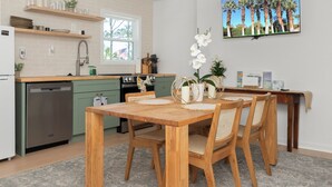 Eine moderne Küche mit Holzschränken, einem Geschirrspüler und einem Essbereich mit einem Holztisch und Stühlen.