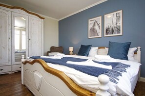 Un dormitorio con una cama grande, un armario y dos cuadros en la pared.