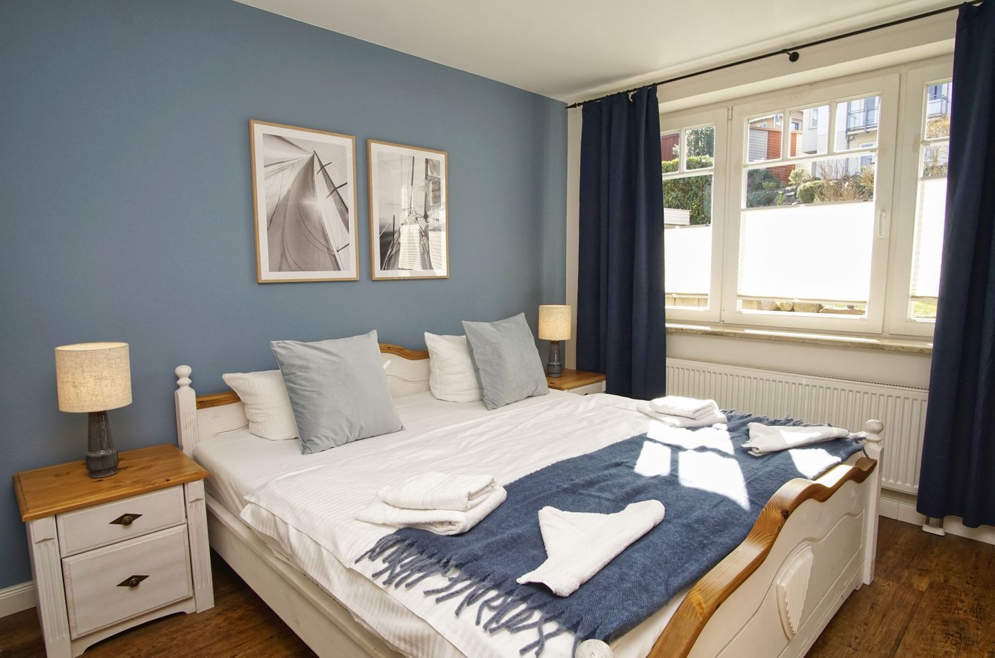 A neatly arranged bedroom with a bed, bedside tables, and a window with curtains.