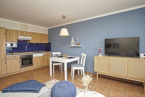 Eine moderne Küche mit Holzausstattung, einem eingebauten Ofen und einem Essbereich mit einem weißen Tisch und Stühlen.