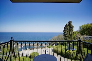 Un balcon avec vue sur la mer, une pelouse et une aire de jeux.