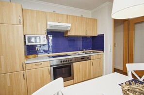 Una cocina compacta con gabinetes de madera, un microondas, una estufa y un lavamanos.