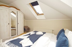 A bedroom with a sloped ceiling, a skylight, a wardrobe, a bed with pillows, and a chair. - Die Ferienwohnung Nr. 09 im Haus am Meer - Haus am Meer (Lohme)
