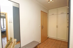 Ein Zimmer mit einer Bank, einem Spiegel, einem Kleiderschrank und einer Tür.