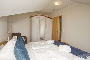 Ein Schlafzimmer mit einem Bett, einem Kleiderschrank und einer Tür zu einem anderen Raum.