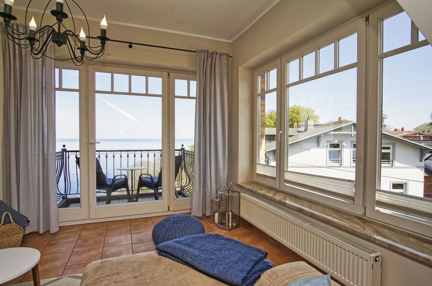A room with a view of the sea, large windows, a balcony with chairs, and a radiator.