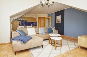 Ein modernes Wohnzimmer mit einer Couch, einem Couchtisch und einer Küchenzeile im Hintergrund.