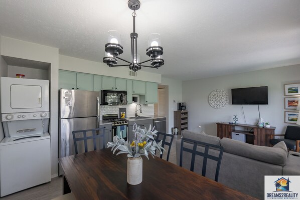 A modern kitchen with a dining area, a flat-screen TV, and a sofa.