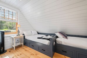 A bedroom with two beds, a desk, and a window with blinds. - The Lake Escape on Rangeley Lake (Rangeley)